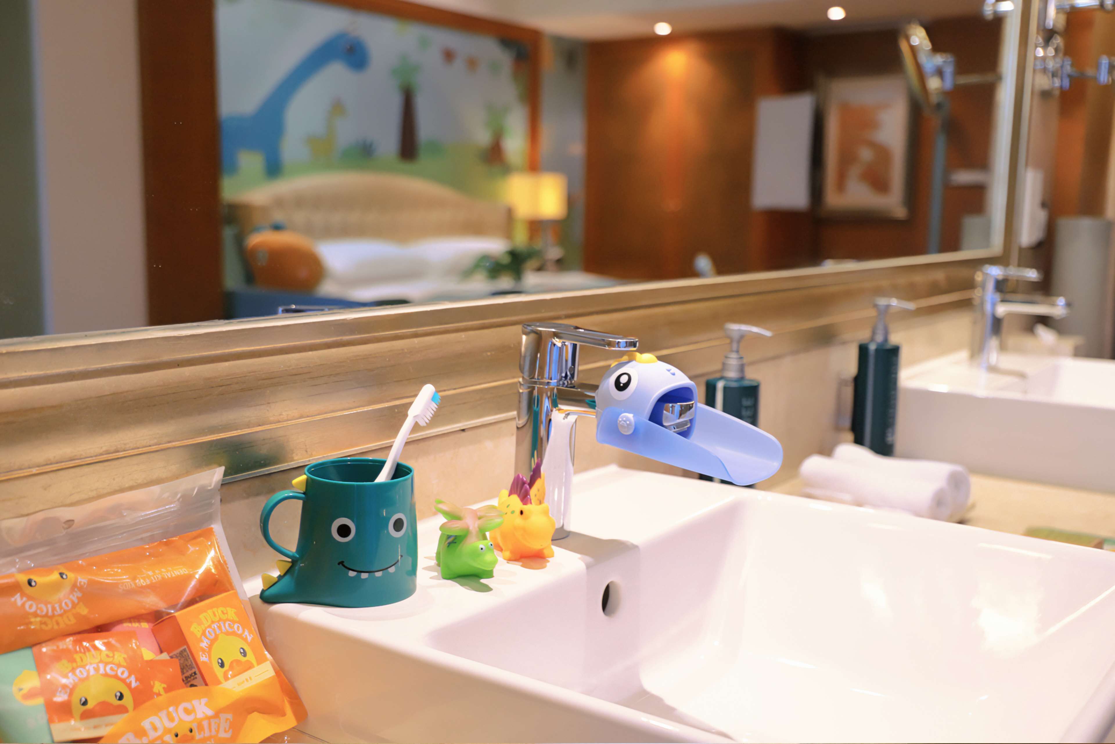 A bathroom with a sink, mirror, and toothbrush holder with duck-themed items.