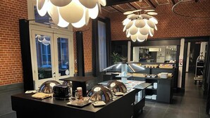 A buffet area with a central island, a reception desk, and a brick wall backdrop. - Zimmerhof Hotel (Lier)