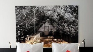 A bed with white and red pillows, a black bedspread, and a large black and white photograph on the wall behind. - Zimmerhof Hotel (Lier)