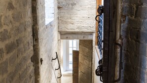 An interior corridor with a stone wall, a wooden door, and a metal gate. - Zimmerhof Hotel (Lier)