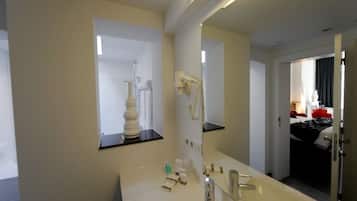 Une salle de bain d’hôtel équipée d’un grand miroir, d’un lavabo, d’un sèche-cheveux et d’un téléphone.