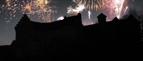 A silhouette of a castle-like structure with fireworks in the background.