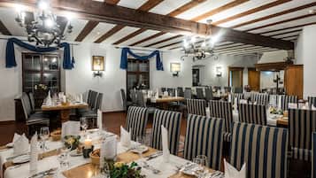 Zona de dinar amb cadires tapissades de ratlles, taules de fusta i lluminàries penjants.