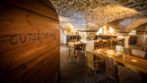 A restaurant interior with wooden walls and a stone ceiling. Tables and chairs are arranged for dining. - Burg Rabenstein (Ahorntal)