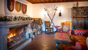 A cozy room with a stone fireplace, wooden beams, and traditional decor. - Burg Rabenstein (Ahorntal)