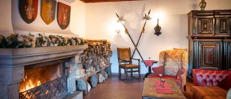 A cozy room with a stone fireplace, wooden beams, and traditional decor.