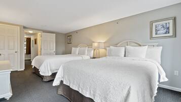 Habitación de hotel con dos camas, un baño y un pasillo.