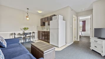 A compact living space with a kitchenette, a sofa, a TV, and a dining area.