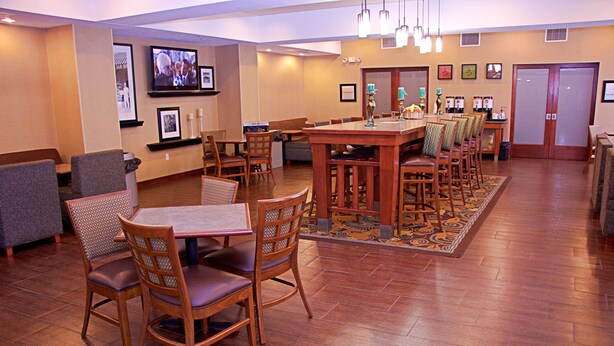 A hotel lobby with a bar area, seating arrangements, and a television mounted on the wall.