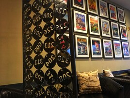 A wall with framed posters and a decorative metal panel with numbers.