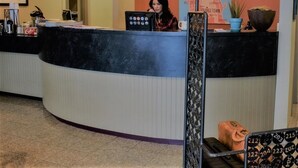 A reception desk with a map of the city on the wall, a potted plant, and a suitcase on the floor. - Georgetown Inn (Seattle)