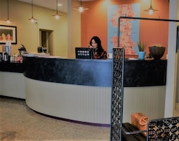 A reception desk with a map of the city on the wall, a potted plant, and a suitcase on the floor.