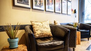 A leather armchair with a patterned cushion, a potted plant, and a wooden stool. - Georgetown Inn (Seattle)