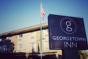 A sign for Georgetown Inn with a flagpole and an American flag.