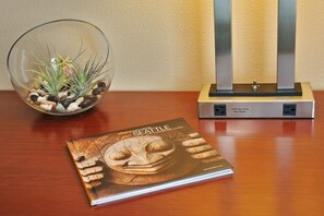 A book titled "Seattle" on a wooden table, a glass bowl with a plant, and a metal stand with a plug.