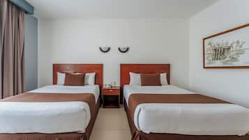 Habitación de hotel con dos camas, una mesita de noche, un reloj en la pared y un cuadro enmarcado.