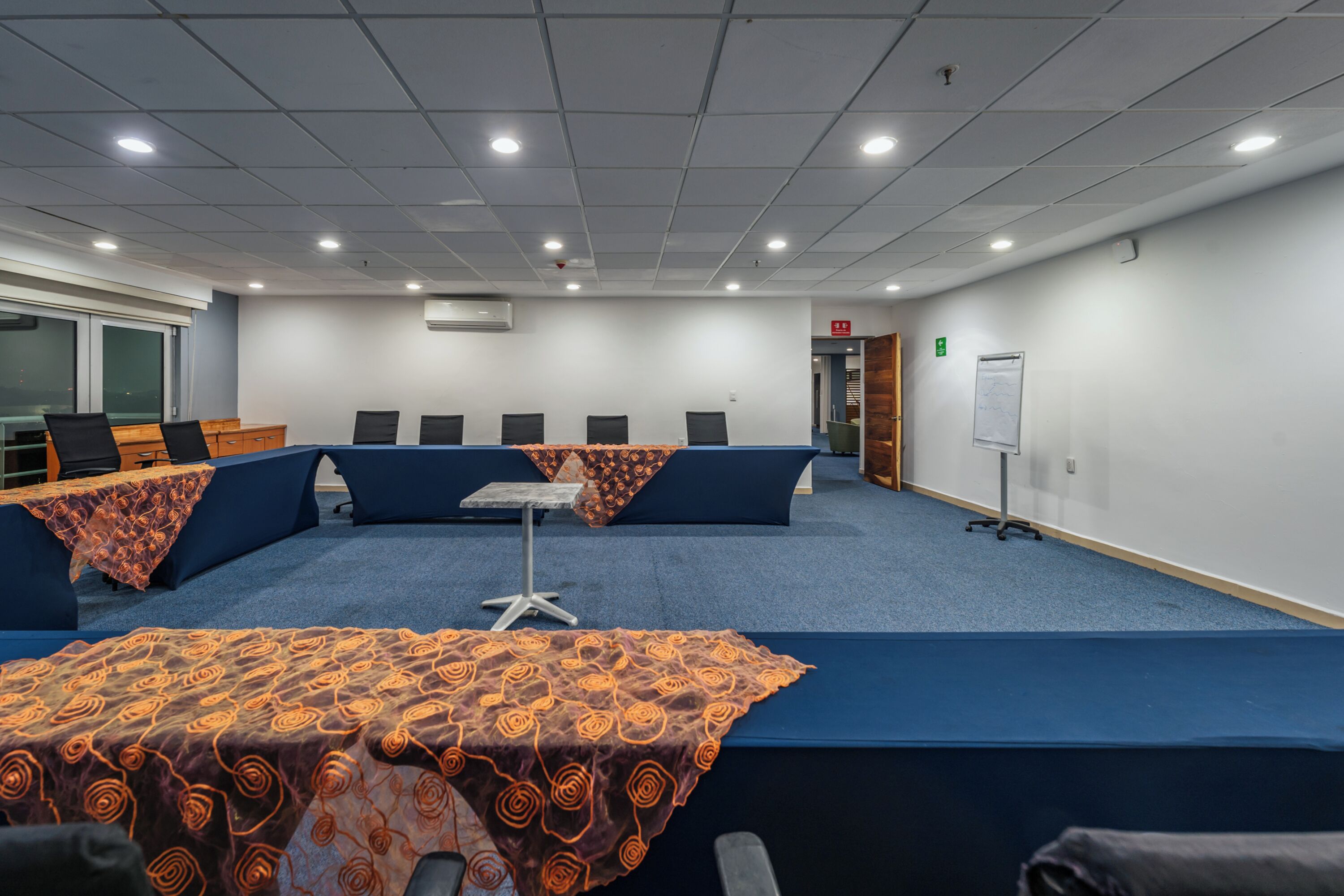 A conference room with a long table, multiple chairs, and a whiteboard on the wall.