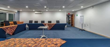 A conference room with a long table, multiple chairs, and a whiteboard on the wall.