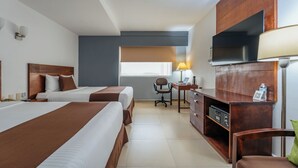 Ein Hotelzimmer mit zwei Betten, einem Schreibtisch, einem Sessel, einem Fernseher und einer Minibar.