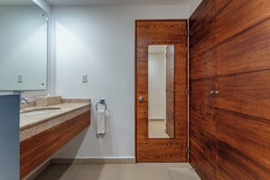 Un baño con tocador de madera, lavamanos y espejo.