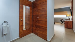 Ein Hotelzimmer mit einem Holzschrank, einem Spiegel, einem Schreibtisch mit Lampe und einem Sessel.