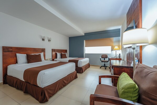 Une chambre d’hôtel avec deux lits, un bureau, une chaise et une lampe.