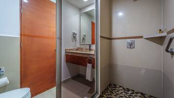 A bathroom with a toilet, a shower, and a sink.
