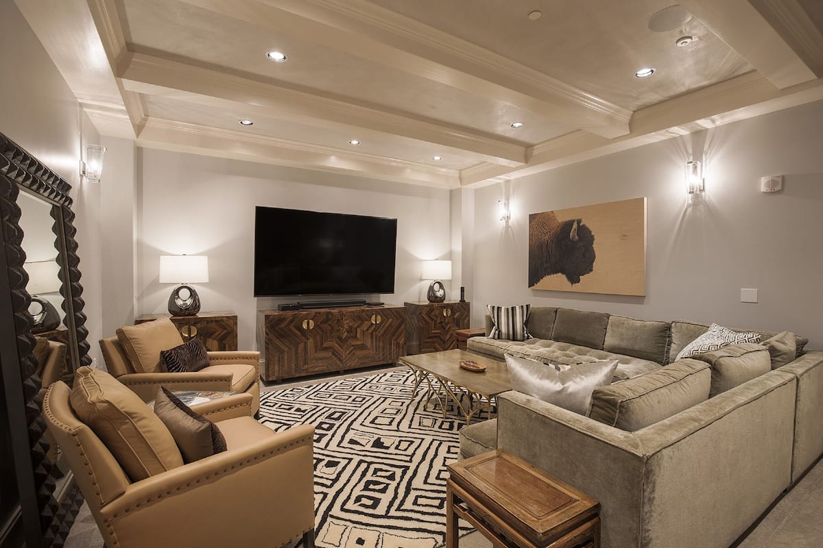 A modern living room with a flat-screen TV, leather sofas, a patterned rug, and wooden furniture.