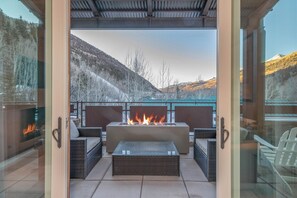 An outdoor patio with a fire feature, wicker furniture, and a view of snow-covered mountains.