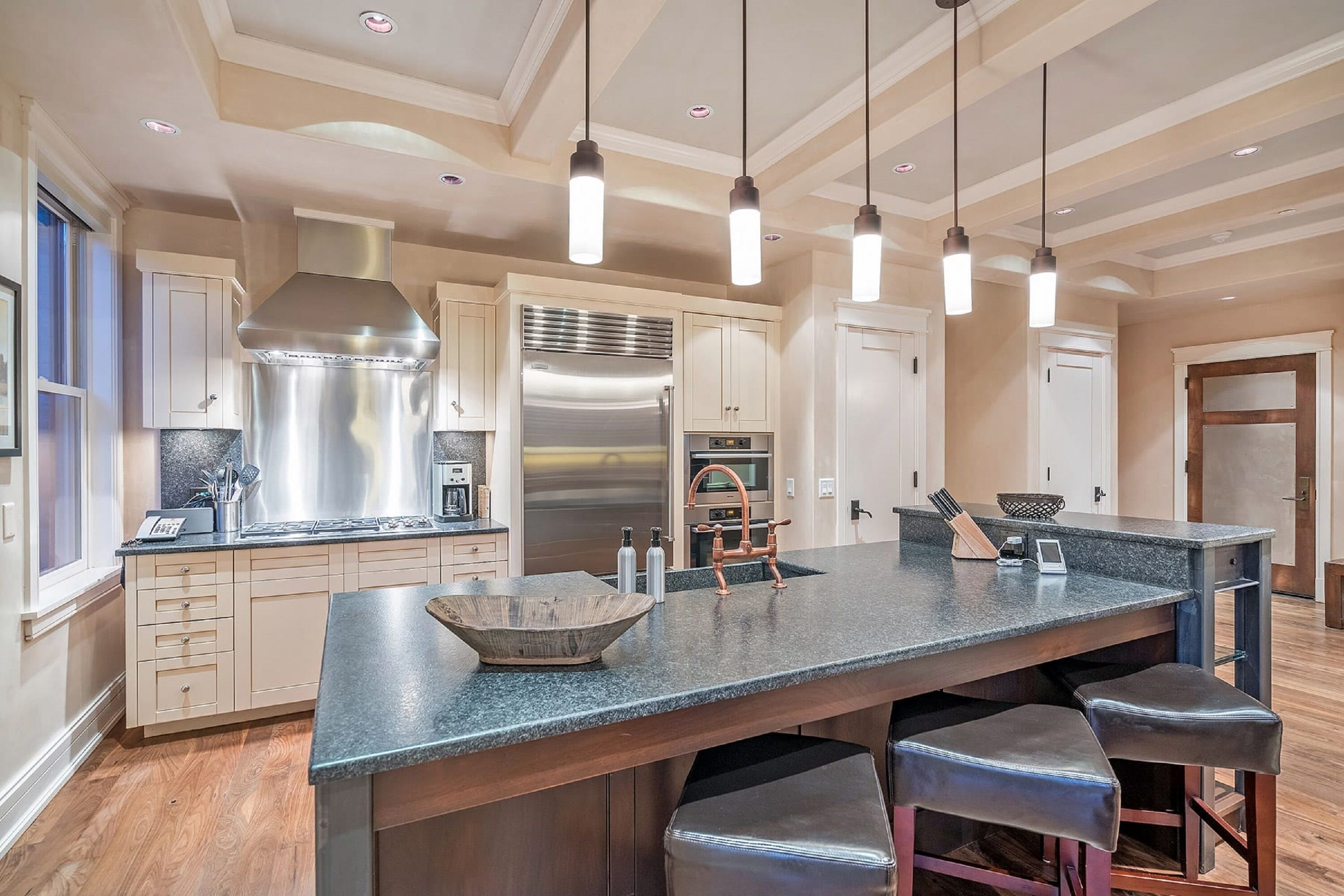 A spacious kitchen with a large island, stainless steel appliances, and pendant lighting.