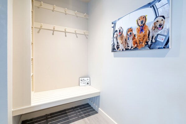 A hallway with a coat rack, a bench, and a framed picture of dogs.