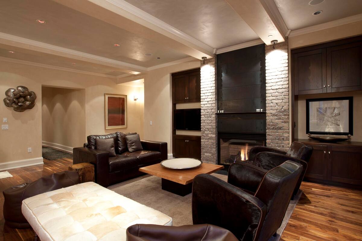 A modern living room with a fireplace, leather furniture, and a flat-screen TV.