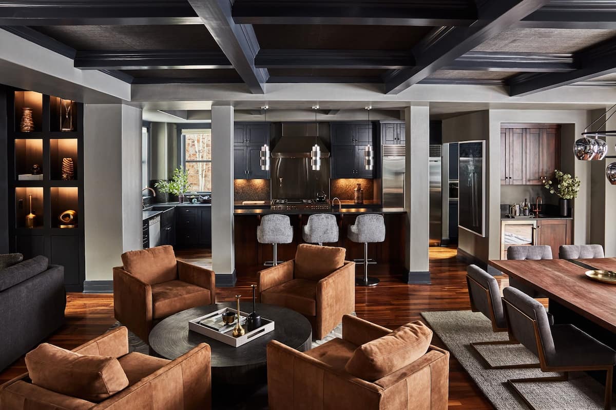 A modern kitchen with dark cabinetry, stainless steel appliances, and pendant lighting.