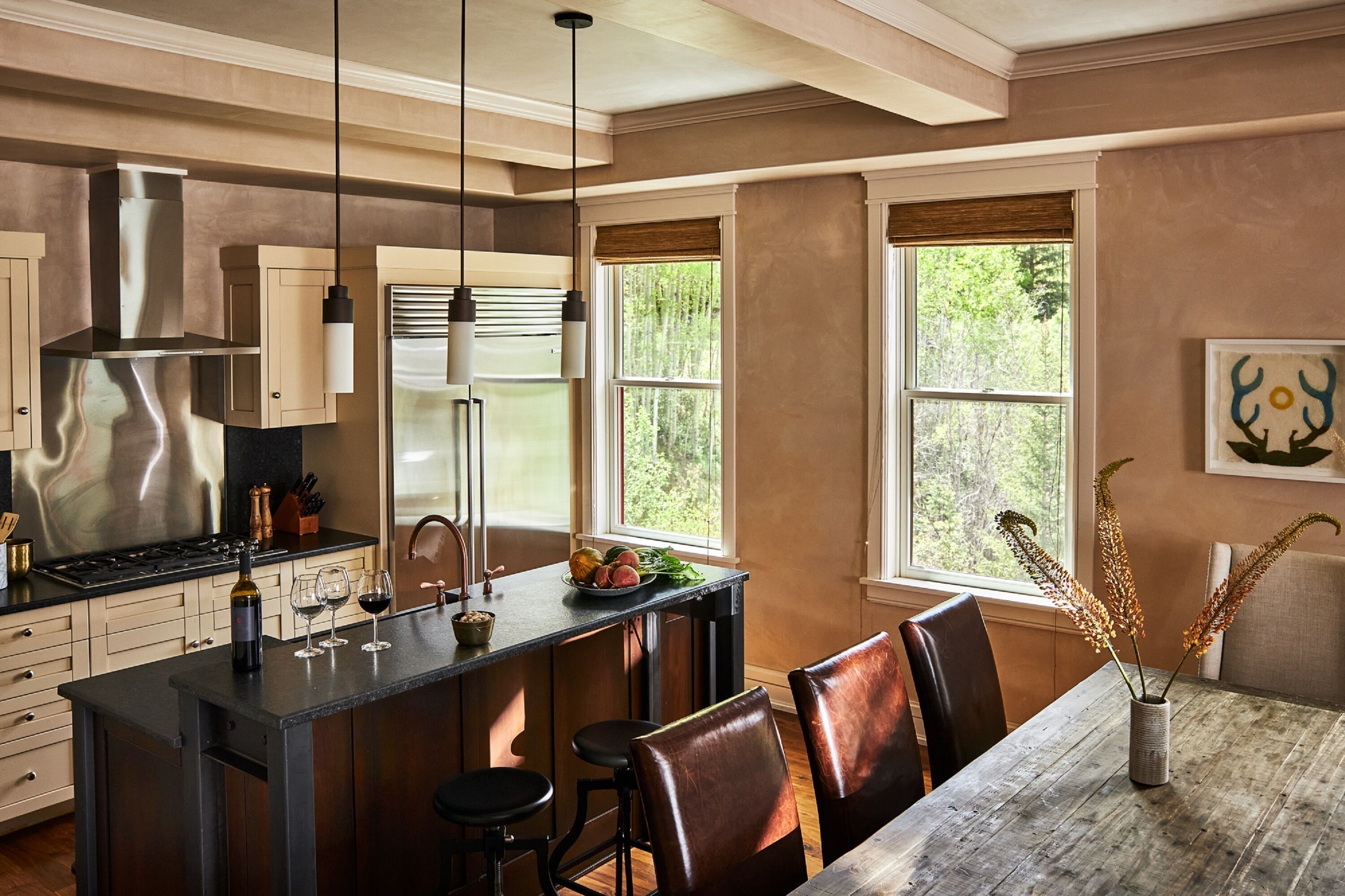 A modern kitchen with a central island, bar stools, and a dining table with chairs.