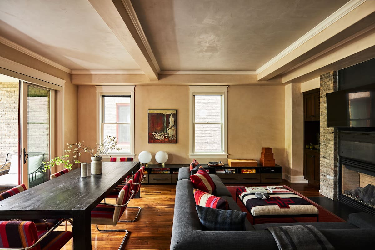 A spacious living room with a long dining table, a sofa set, and a fireplace.
