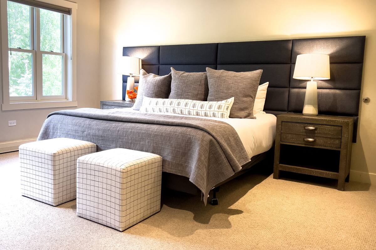 A bedroom with a large bed, two bedside tables, a nightstand, and a window.