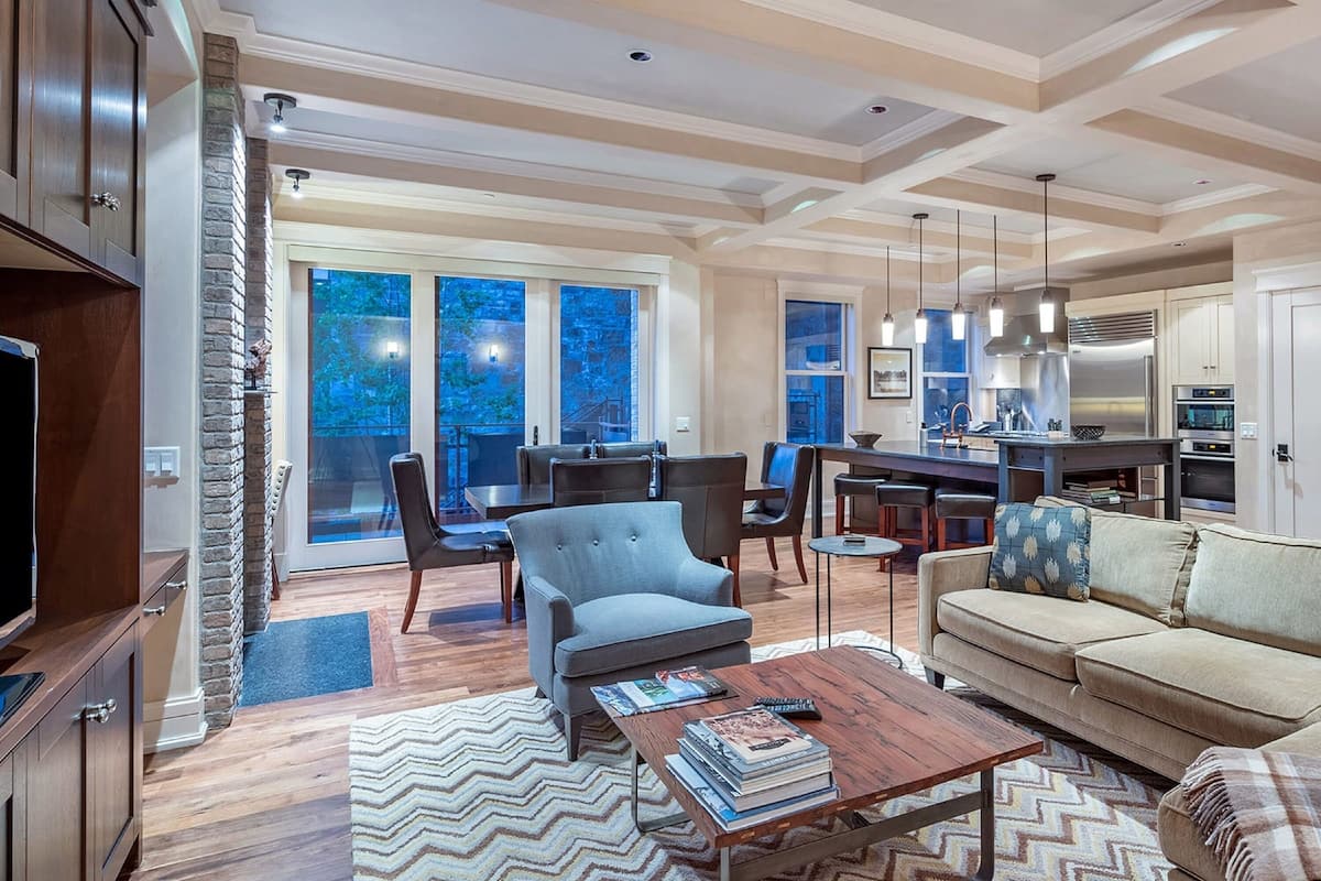 A spacious living area with a sofa, armchair, and coffee table, a dining area with chairs, and a kitchen with modern appliances.