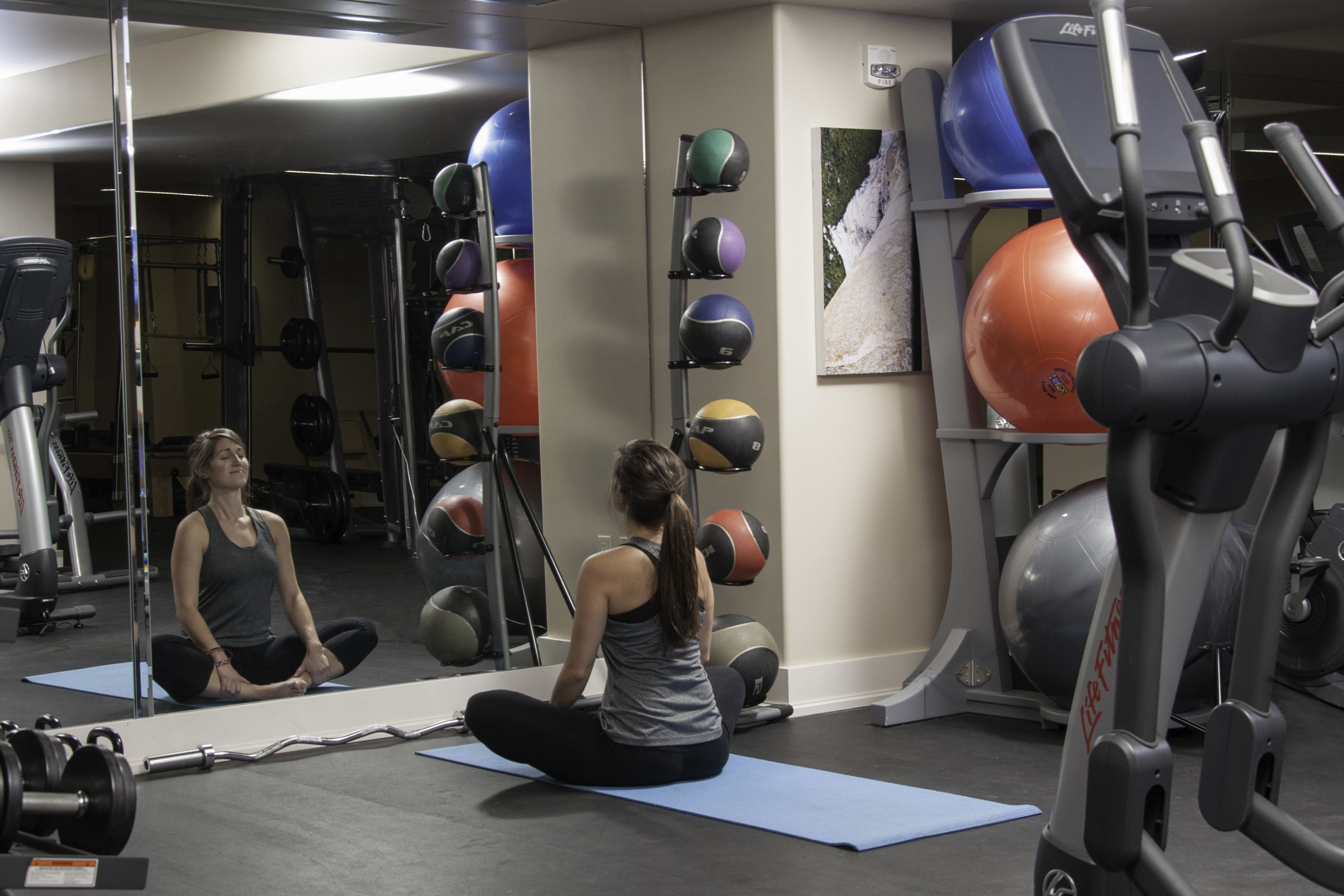 Une salle de sport équipée de matériel d’exercice, d’un miroir et d’un tapis de yoga.