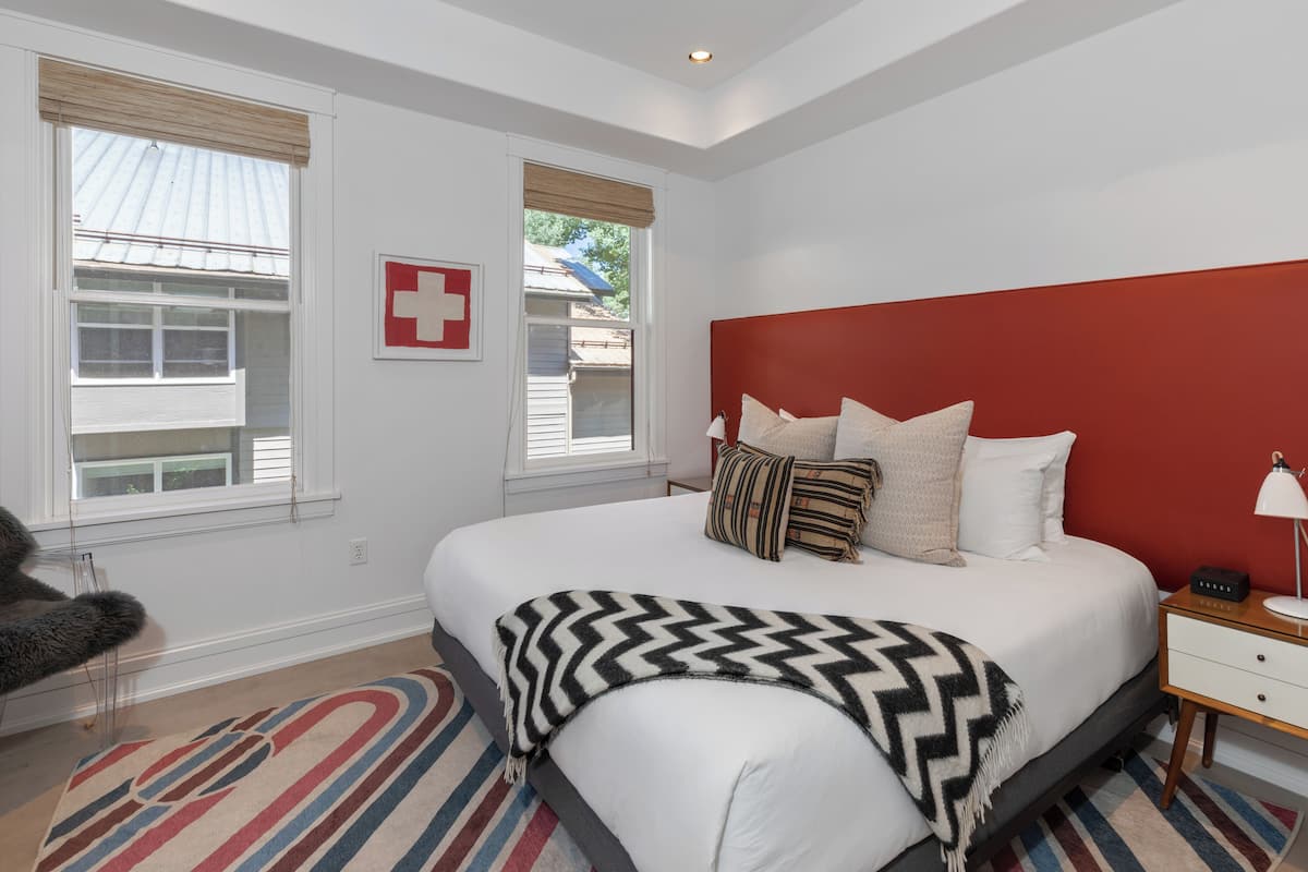 A bedroom with a large bed, a red headboard, and a bedside table with a lamp.