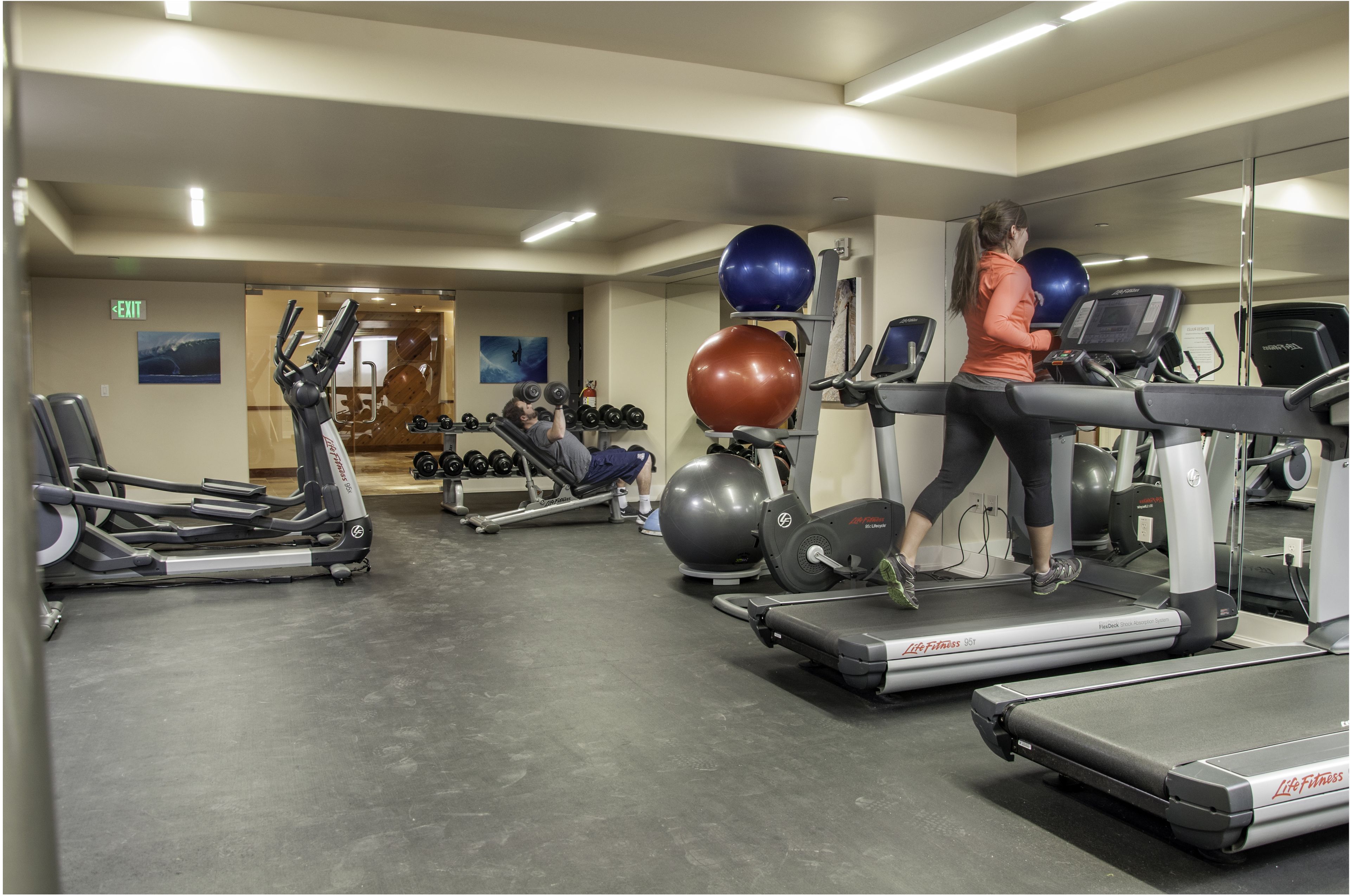 Une salle de sport équipée de tapis de course, d’haltères et de ballons d’exercice.