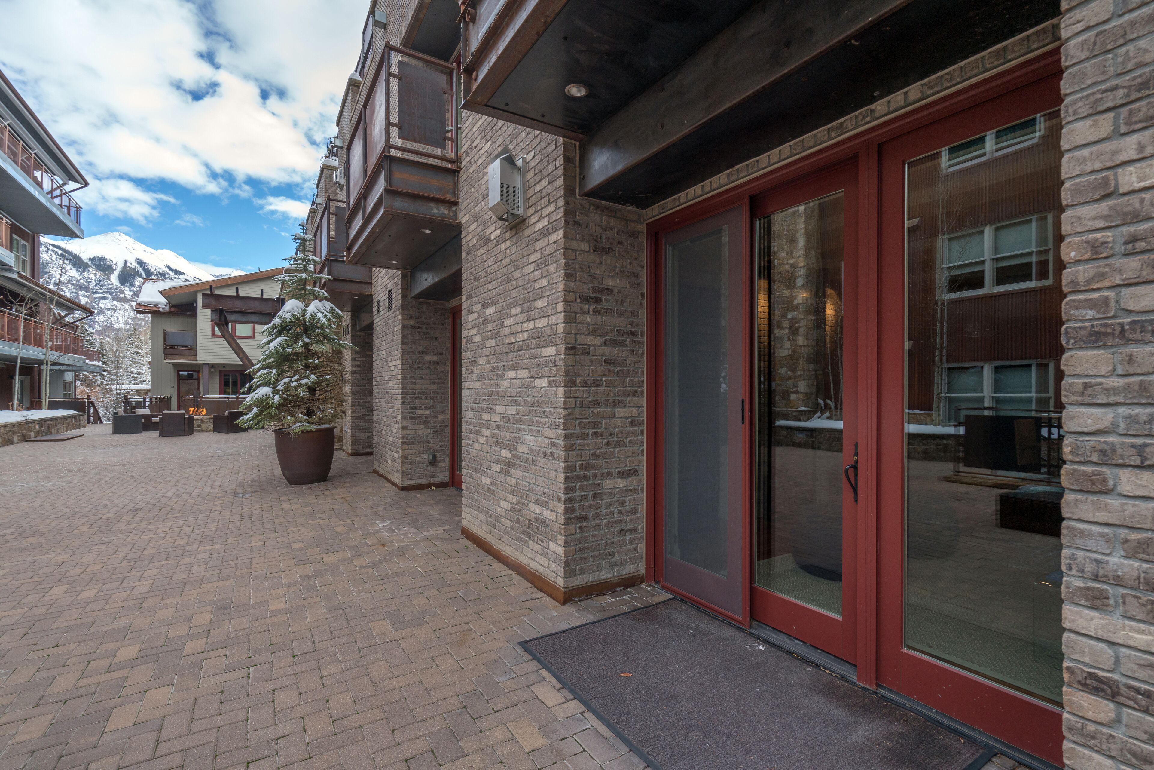 A building with a brick facade, large glass doors, and a snow-covered mountain in the background.