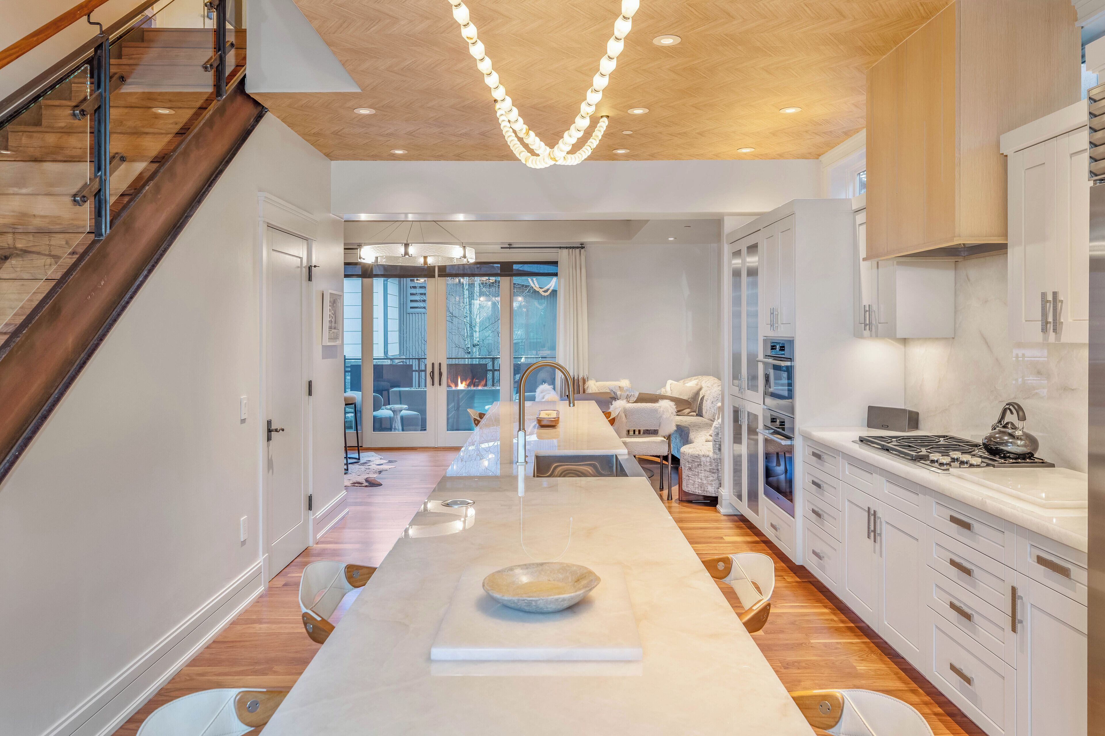 A modern kitchen with a central island, wooden flooring, and white cabinetry.