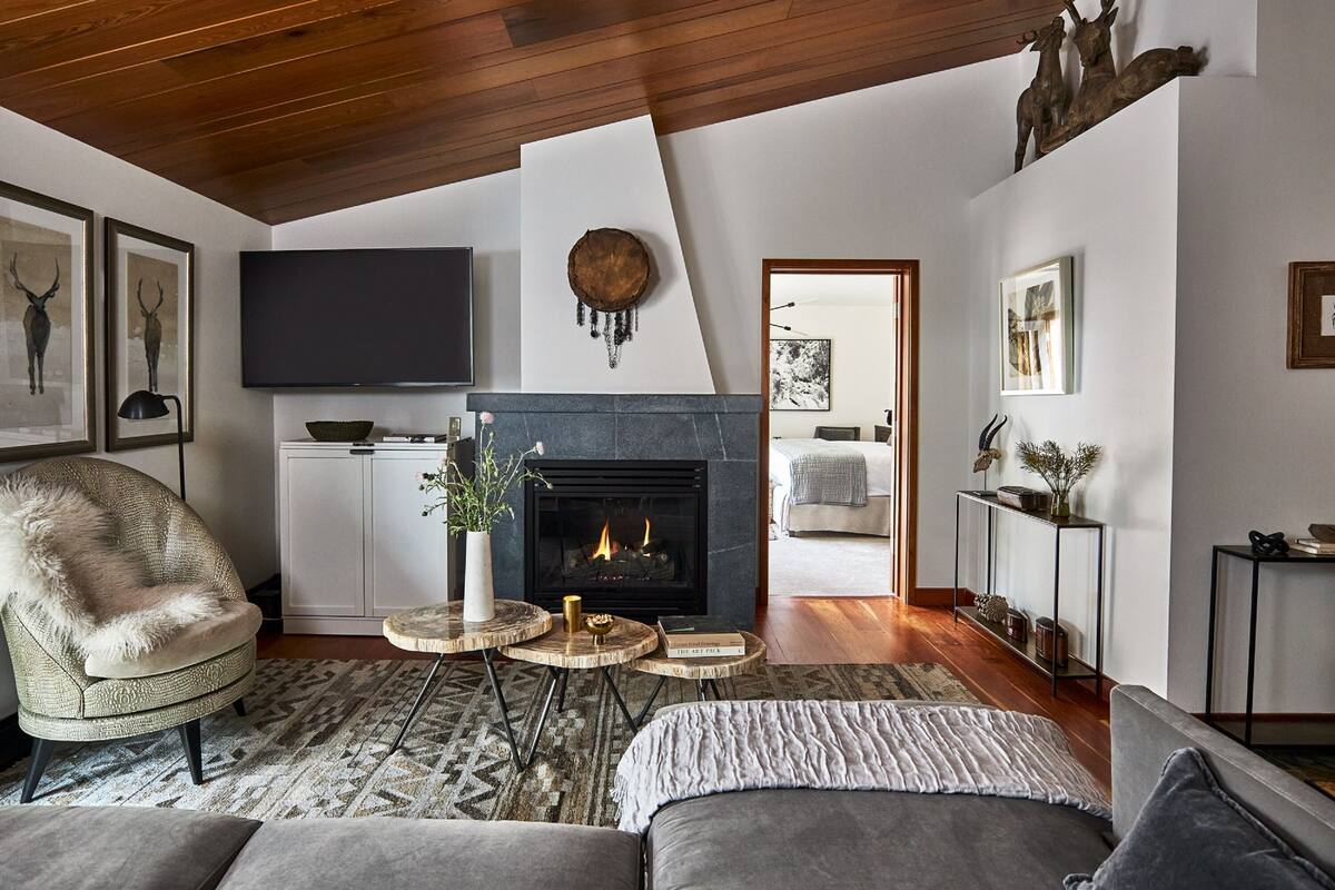 A modern living room with a fireplace, a flat-screen TV, and a cozy seating area.