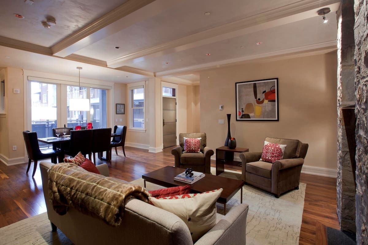A spacious living room with a fireplace, a dining area with a table and chairs, and a large window providing natural light.