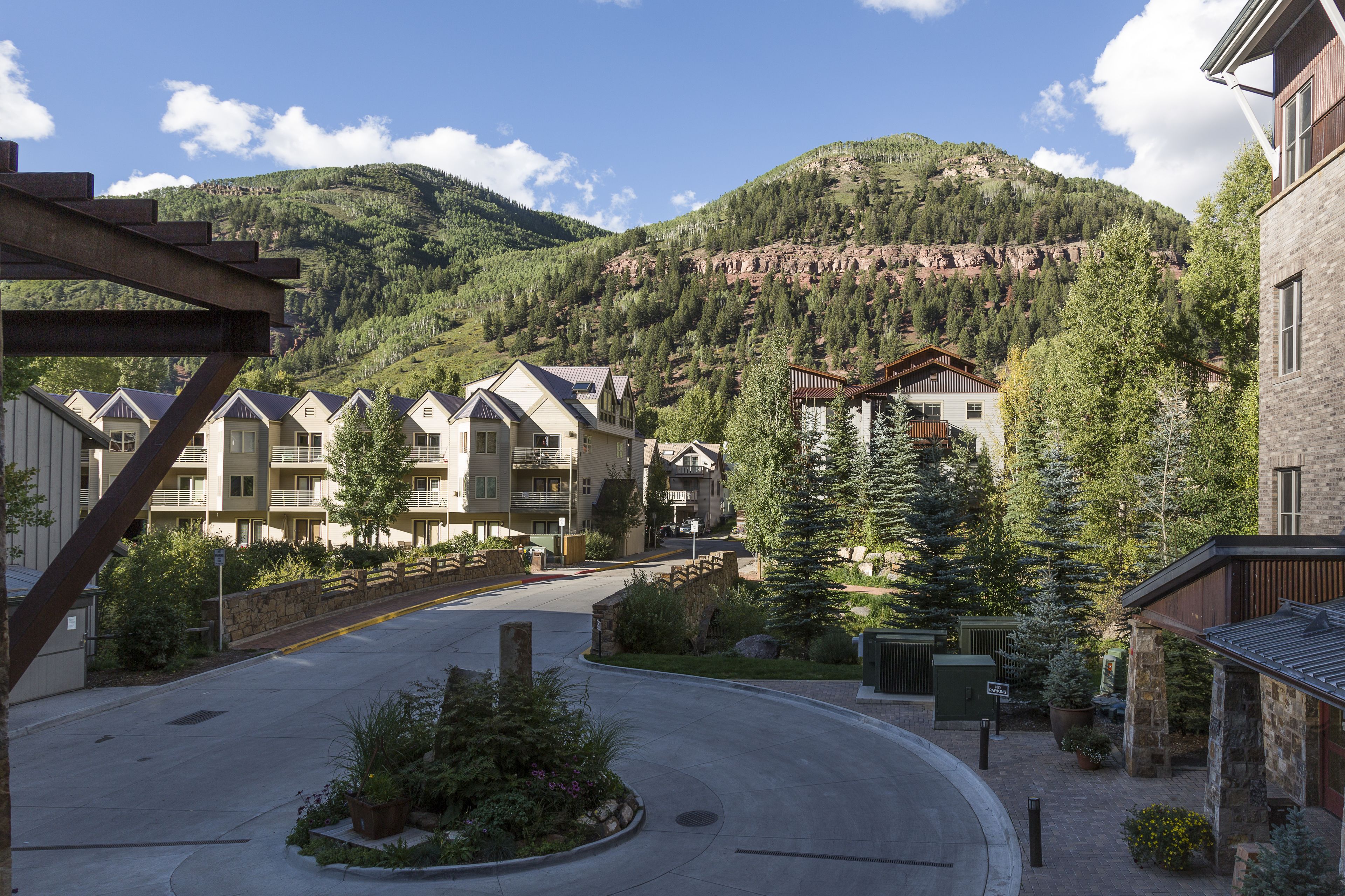 Un quartier résidentiel avec une route sinueuse, des maisons dotées de balcons et une montagne en arrière-plan.
