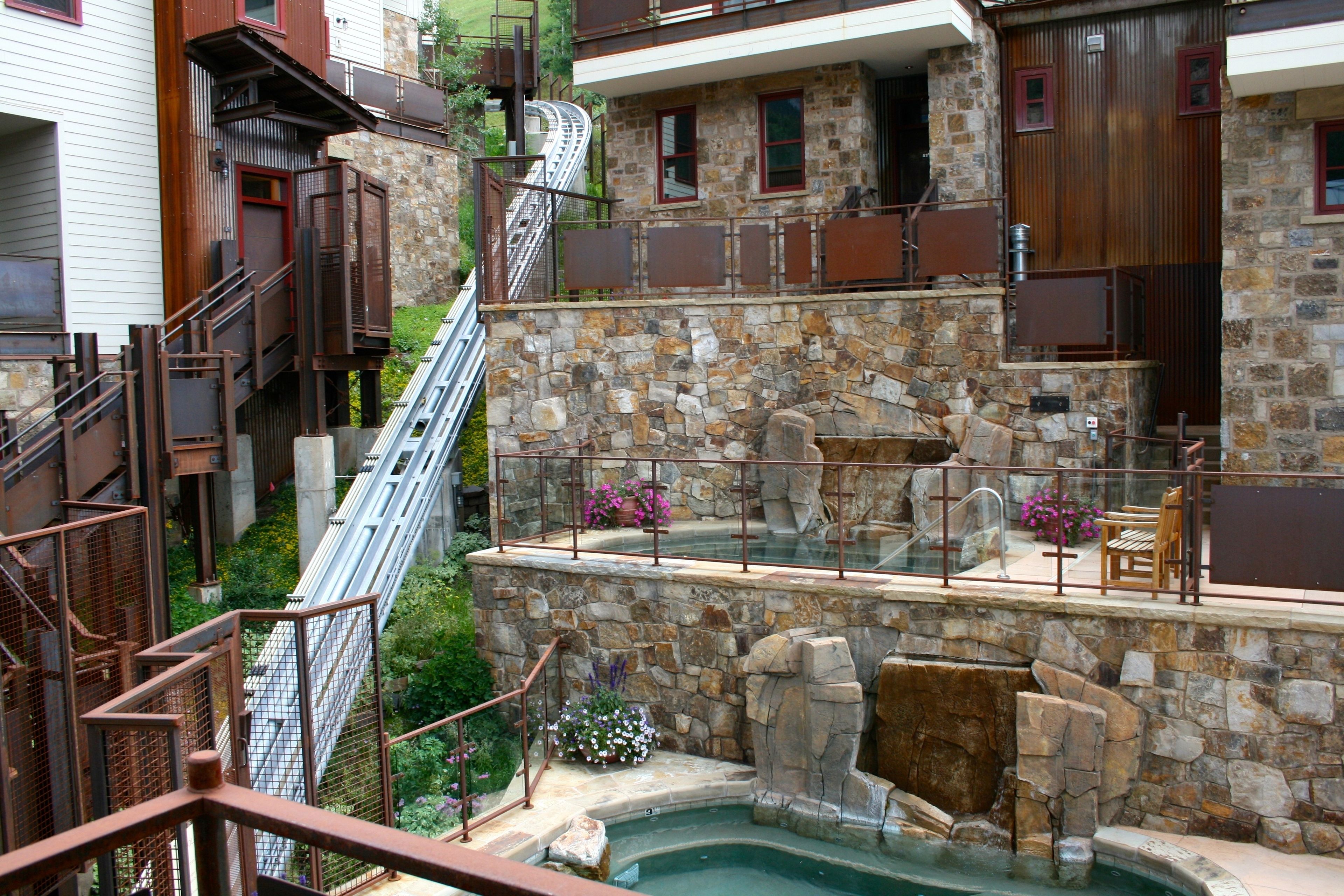 A stone-walled outdoor hot tub area with a metal staircase and a glass balustrade.