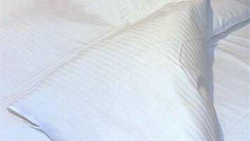 A neatly made bed with white linens.