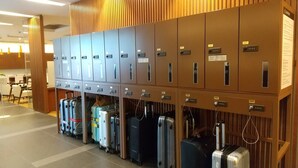 A row of luggage storage lockers with multiple suitcases placed underneath. - JR Inn Sapporo (Sapporo)