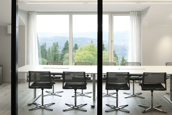 A conference room with a large table and six black chairs, large windows with a view of trees and mountains, and a modern interior design. - Lysebu Hotel (Oslo)
