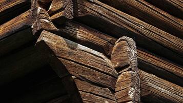A close-up of a wooden log cabin's exterior with a distinctive spiral staircase design.